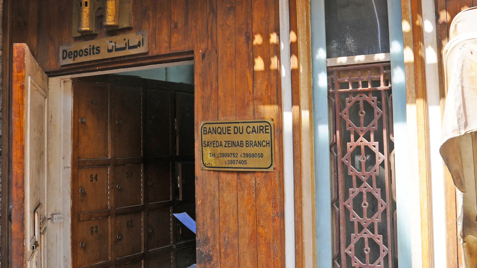 The carved wooden doorway and brass plaque of a Banque du Caire branch in Cairo’s Sayeda Zeinab district
