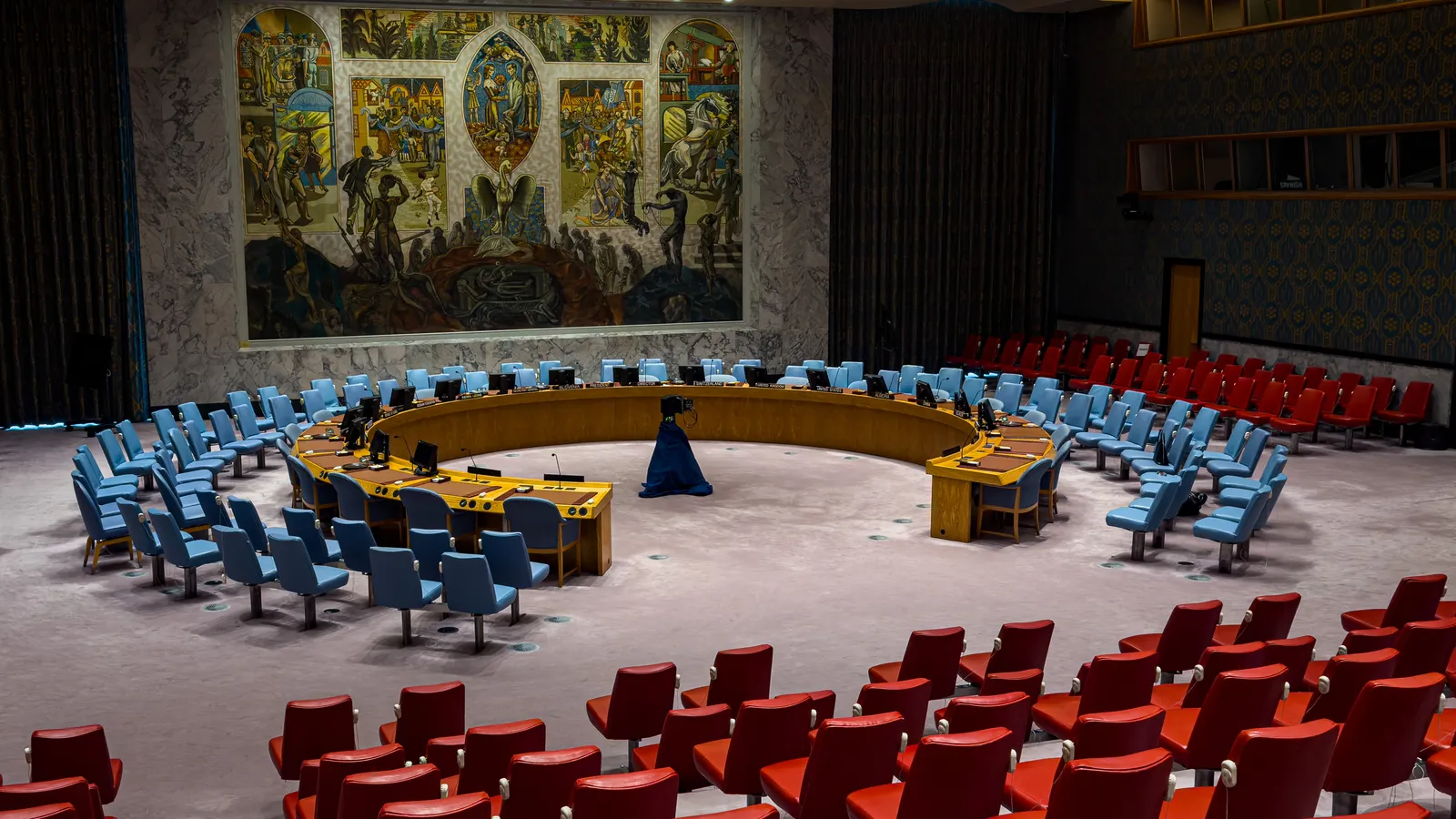 The empty UN Security Council chamber in New York, with its horseshoe table and large mural
